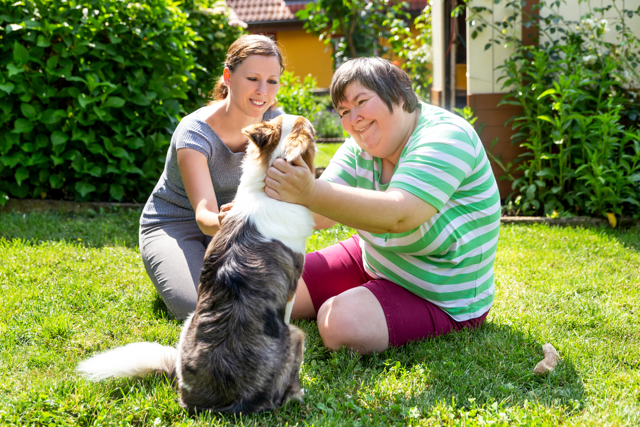 two women petting a dog outdoors