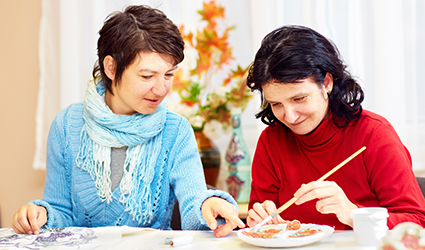 a woman assisting another woman painting