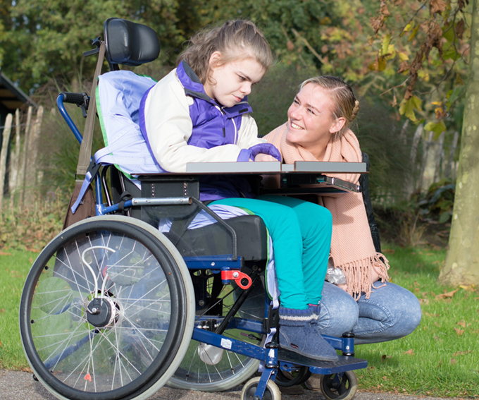 person using a wheelchair with person sitting next to chair