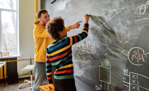 Teacher ane student practice mathematics on a blackboard