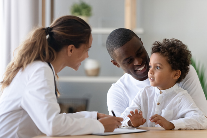 child and father talking to a pediatrician