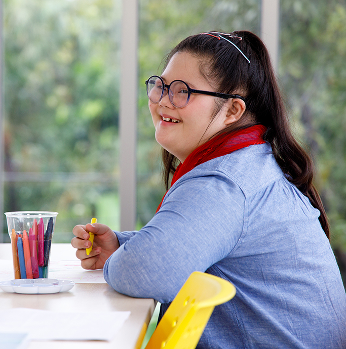 smiling girl with disabilities drawing a picture