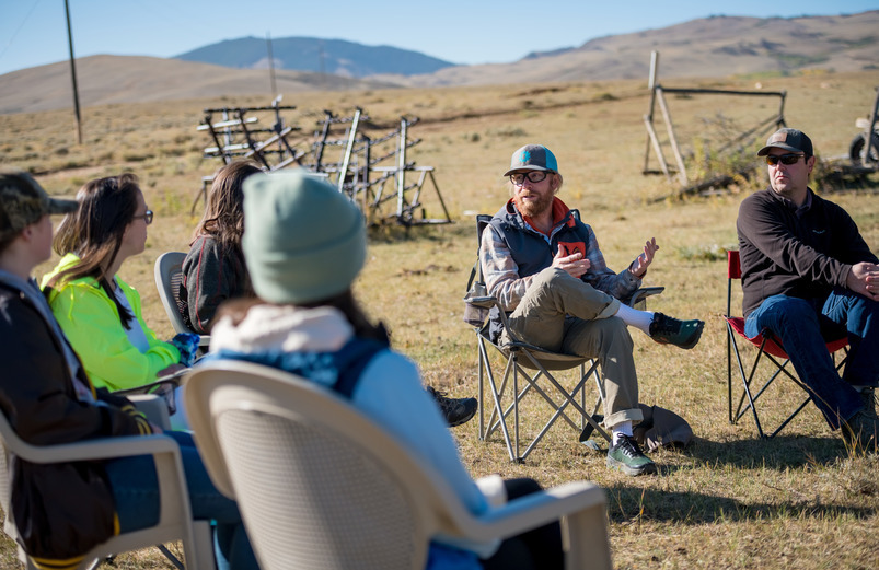 A group of people sitting in chairs outside and talking.