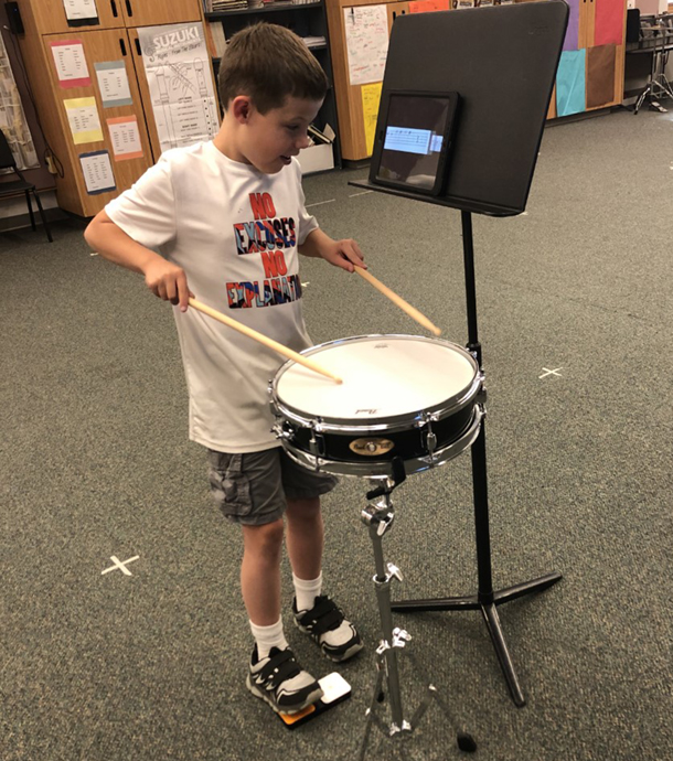 boy playing drums using iPad to read music