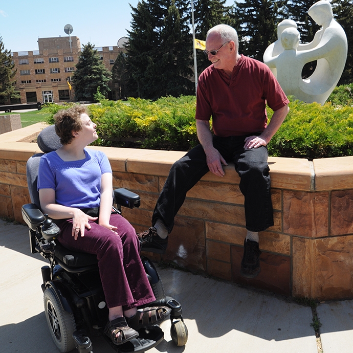 man talking to woman in powerchair