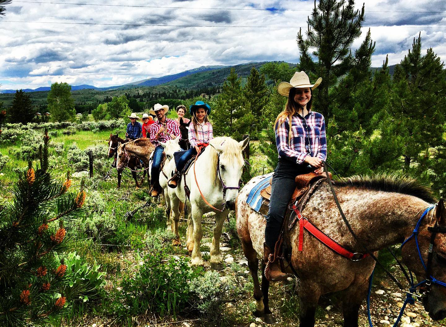 People riding horses with mountains in the background