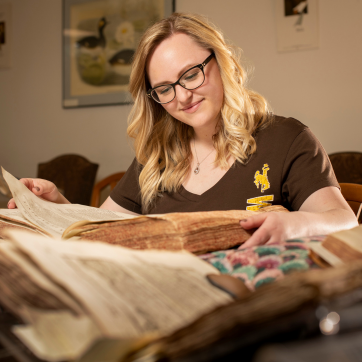 A woman reads from an old book. 