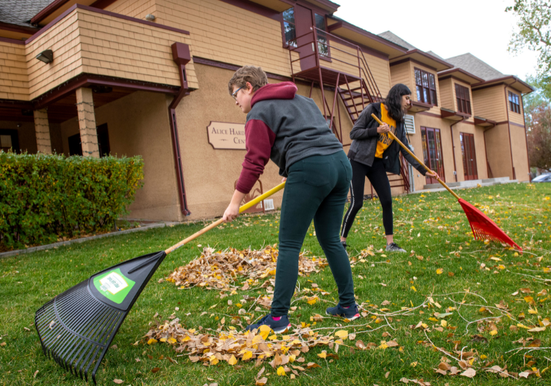 Two girls rake leaves