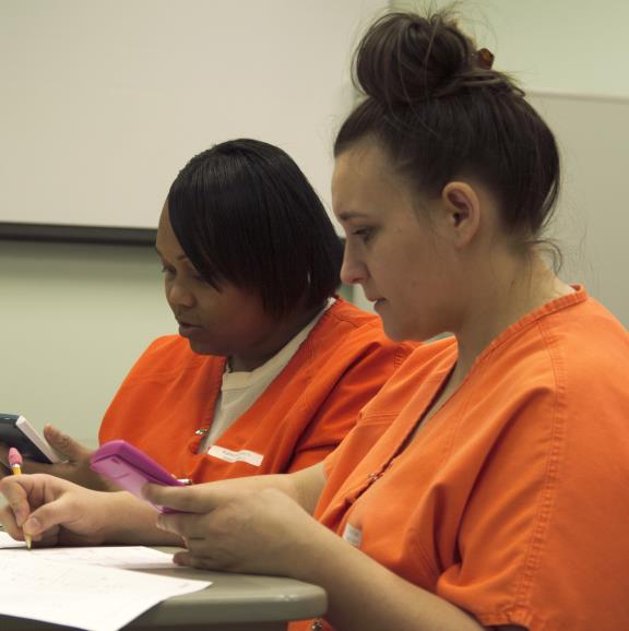 Two students from the Wyoming Women's Center complete math assignments with calculators.