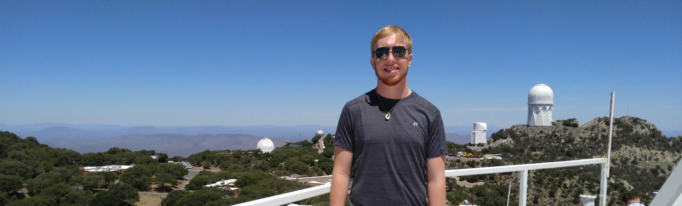 student on telescope platform against blue sky