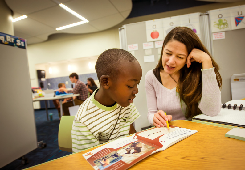 Photo of woman working on reading with a child.