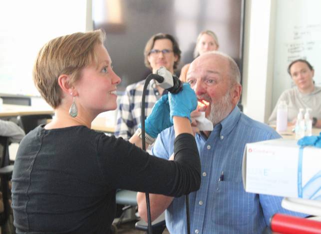 A woman using an oral ultra sound device on an older man.