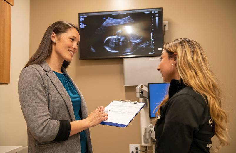 Doctor talking to a patient with an image of an ultrasound in the background.