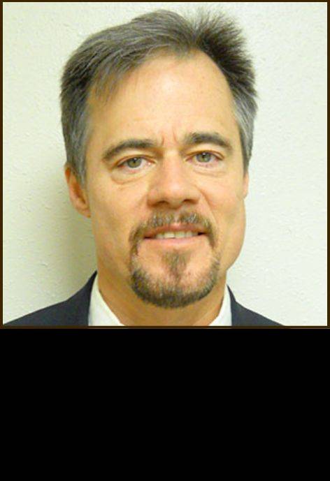 Dr. Douglas Edgren, wearing a black suit jacket with a white button-up shirt.