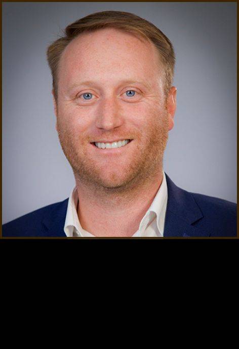 Dr. Rage Geringer, wearing a blue suit jacket and a white button-up shirt.