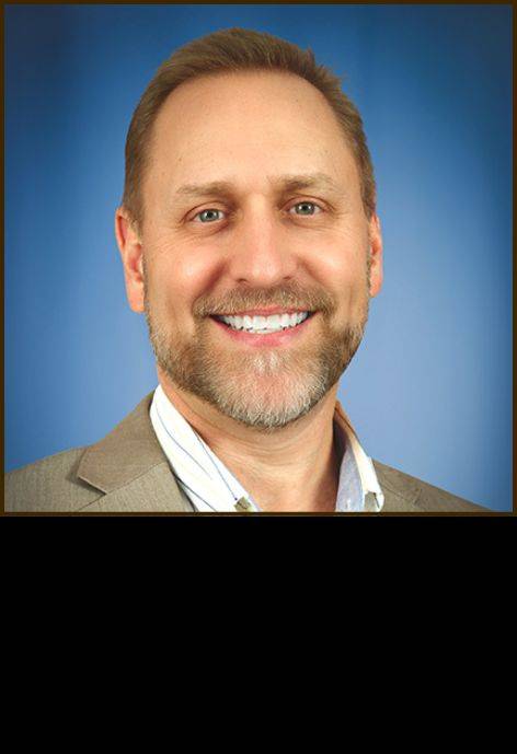 Dr. Brian Horst, wearing a tan suit jacket and a white button-up shirt.