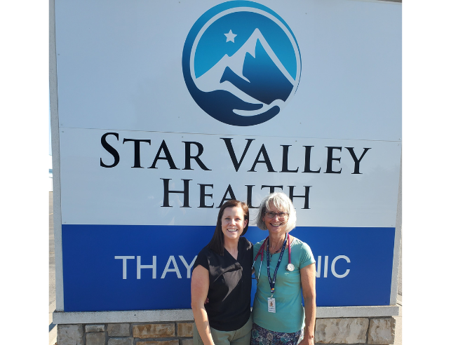 Two people standing together in front of a sign that reads, "Star Valley Health".