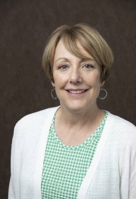 Julie Carlson, wearing a green and white checkered blouse and a white caridgan.