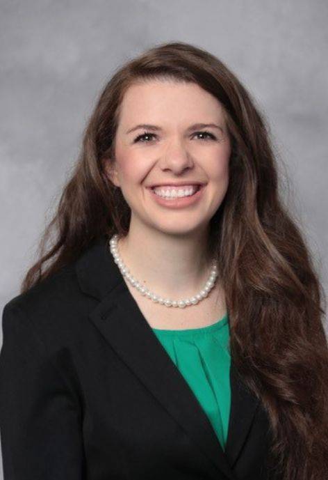 Janelle T. Fried, wearing a black suit jacket and a mint green blouse.