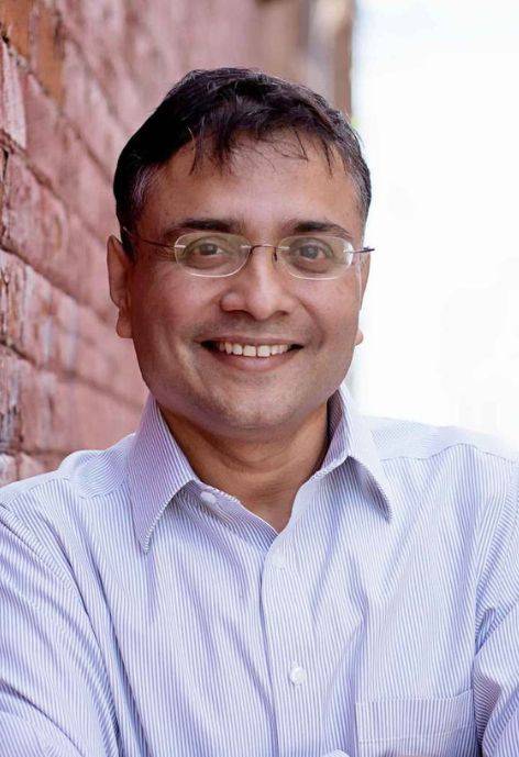 Sreejayan Nair, wearing a blue and white striped button-up shirt.