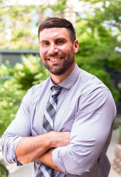 Tyler Gallo, wearing a light purple button-up shirt and a silver striped tie.