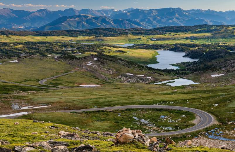 A green landscape with a river and mountains.