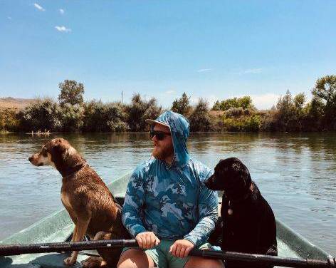 Ross Cook on a row boat with his two dogs.