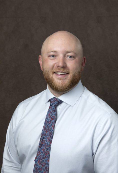 Ross Cook, wearing a white button-up and a floral tie.