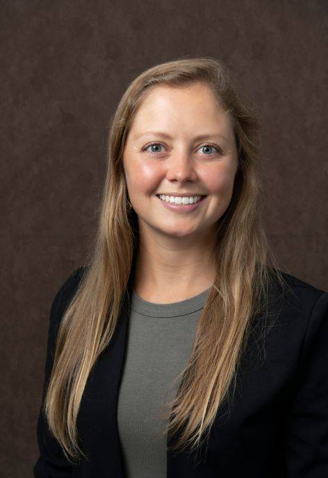 Jenni Ebersberger, wearing a black suit jacket and a grey shirt.