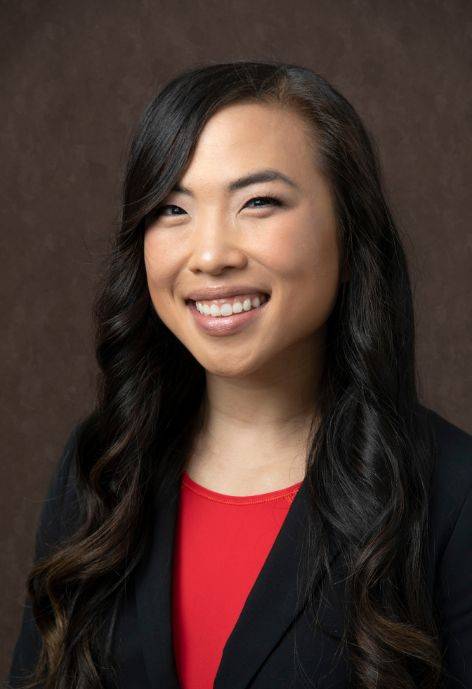 Daphne Ma, wearing a black suit jacket and a red blouse.