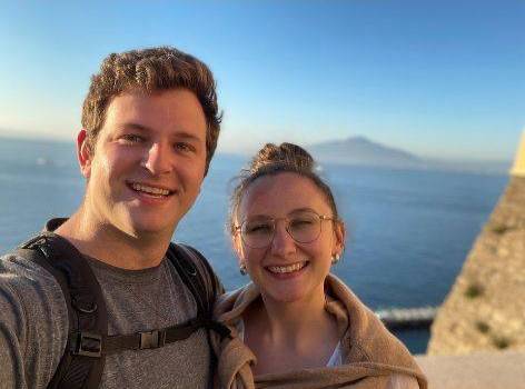 Maddy with her husband, behind them is the ocean.