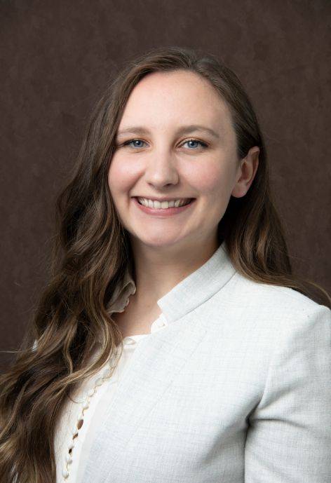 Maddy Prince, wearing a light grey suit jacket and a white blouse.