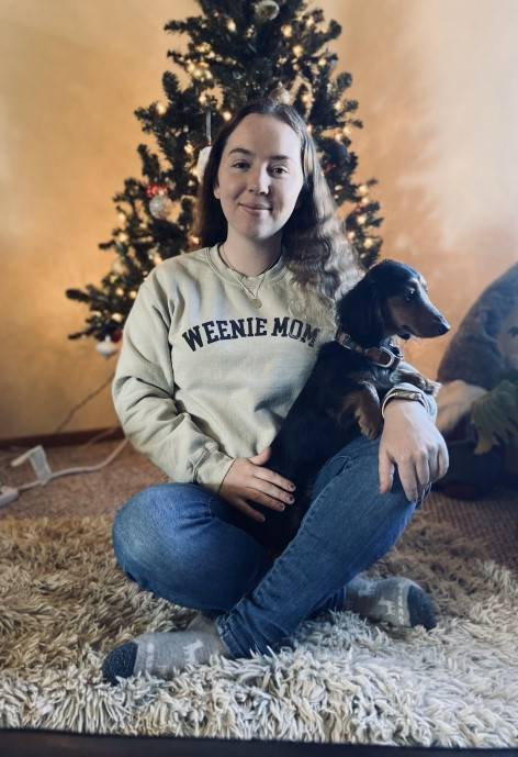 Chantelle sitting on a shag rug holding a dachshund.