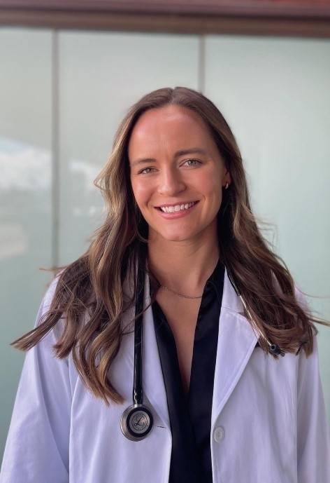 Clara wearing a doctor's coat and smiling at the camera.
