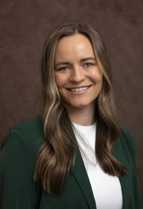 Clara Bouley wearing a dark green jacket and a white blouse.