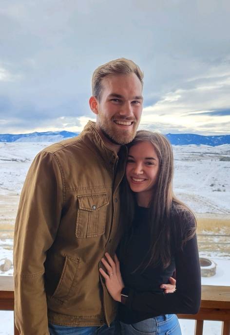 Quinton standing with a woman outside, they are both smiling at the camera.