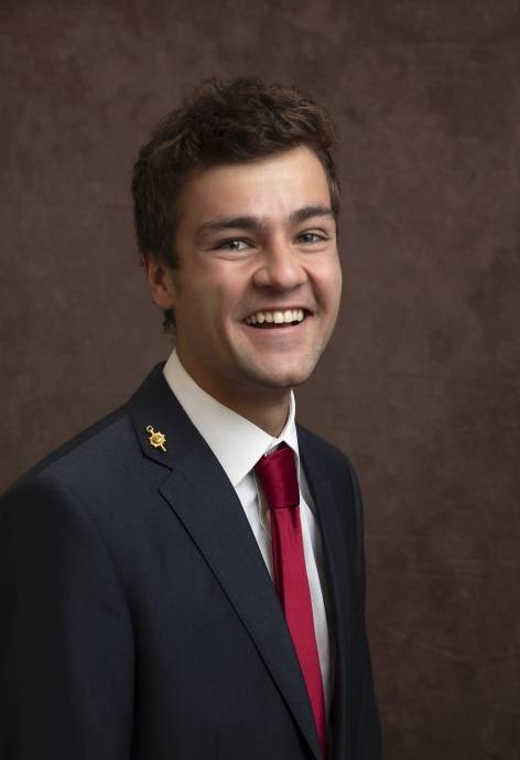 Brad Burns wearing a black suit jacket, white button-up, and red tie.