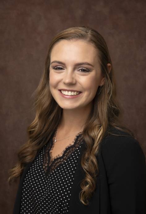 Rylie Pilon wearing a black jacket and a black and white polka-dot blouse.