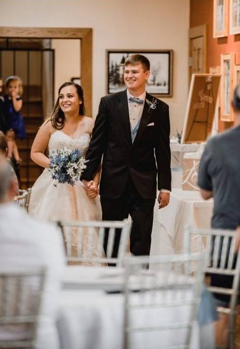 Tatiana at her wedding holding hands with her husband.