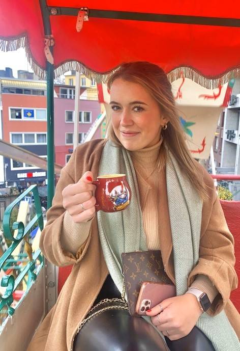 Tori sitting under a red umbrella holding a mug.