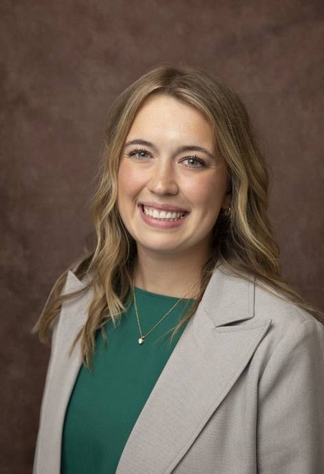 Victoria Toscana wearing a light grey jacket and a green blouse.