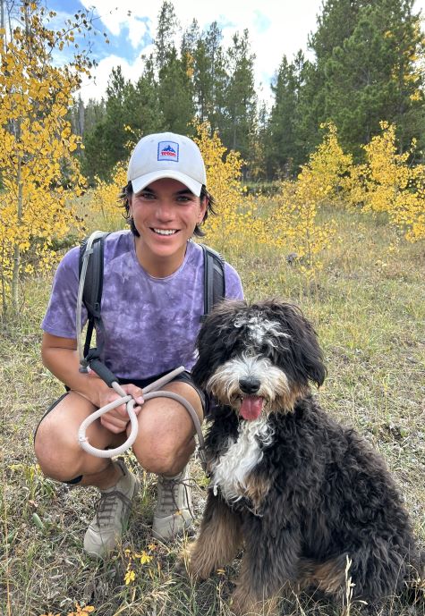 Kyler with a dog, outside in a forest.