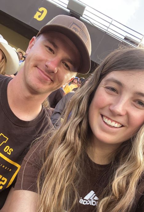Shay taking a selfie with her husband at a football game.