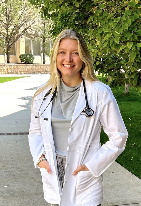 Aedian standing outside wearing a doctor's coat.