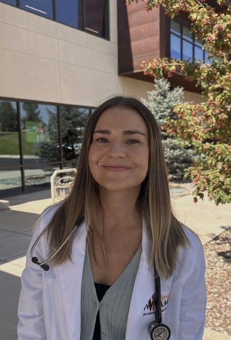 Audrey standing outside of a hospital and wearing a doctor's coat.