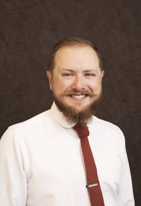 Jack Syring wearing a white button-up and a red tie.