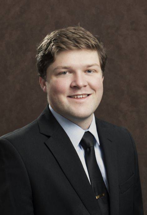 Easton Couch wearing a black suit jacket, light blue button-up, and black tie.