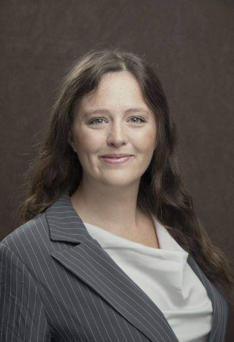 Elizbeth Girling wearing a black pin strip jacket and a white blouse.