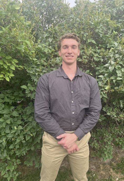 Winston standing in front of a tall bush.