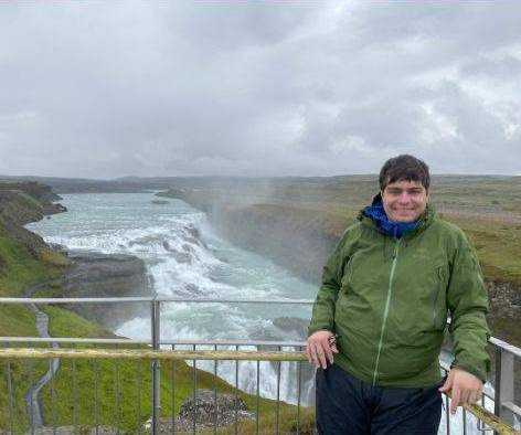 Dalton standing on a bridge with a waterfall in the background.